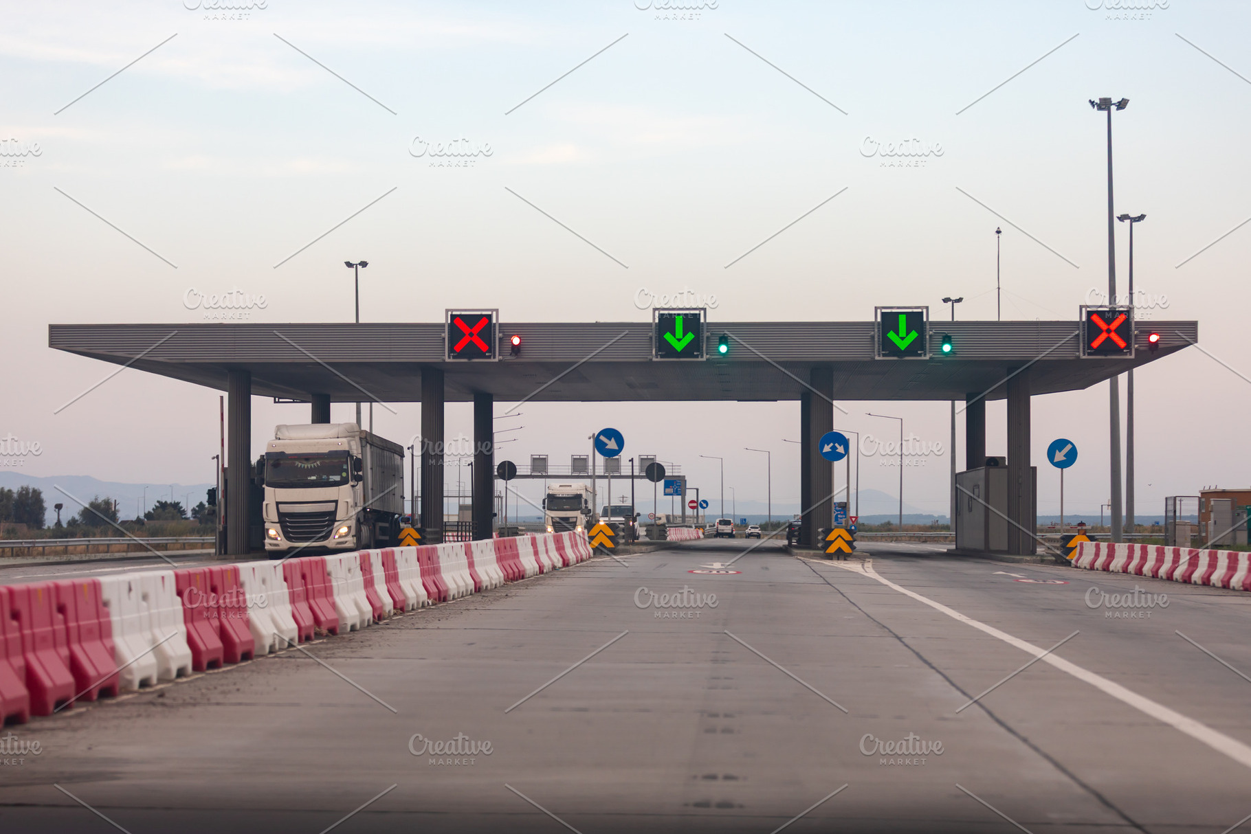 Contemporary highway toll plaza with trucks and illuminated signals under a cle, a Transportation Photo by Ales Munt