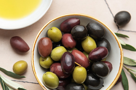 Bowl of assorted olives with olive oil and olive branches on til, a Food & Drink Photo by Olena Rudo