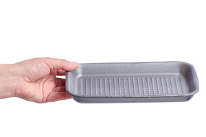 A woman's hand holding an empty grey foam food tray on isolated, a Food & Drink Photo by ndanko