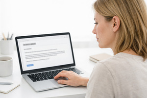 Woman working on laptop at desk in m, a Photo by Dvoevnore photos