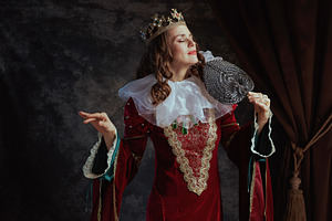 medieval queen in red dress with fan, white collar and crown, a Person Photo by Alliance Images