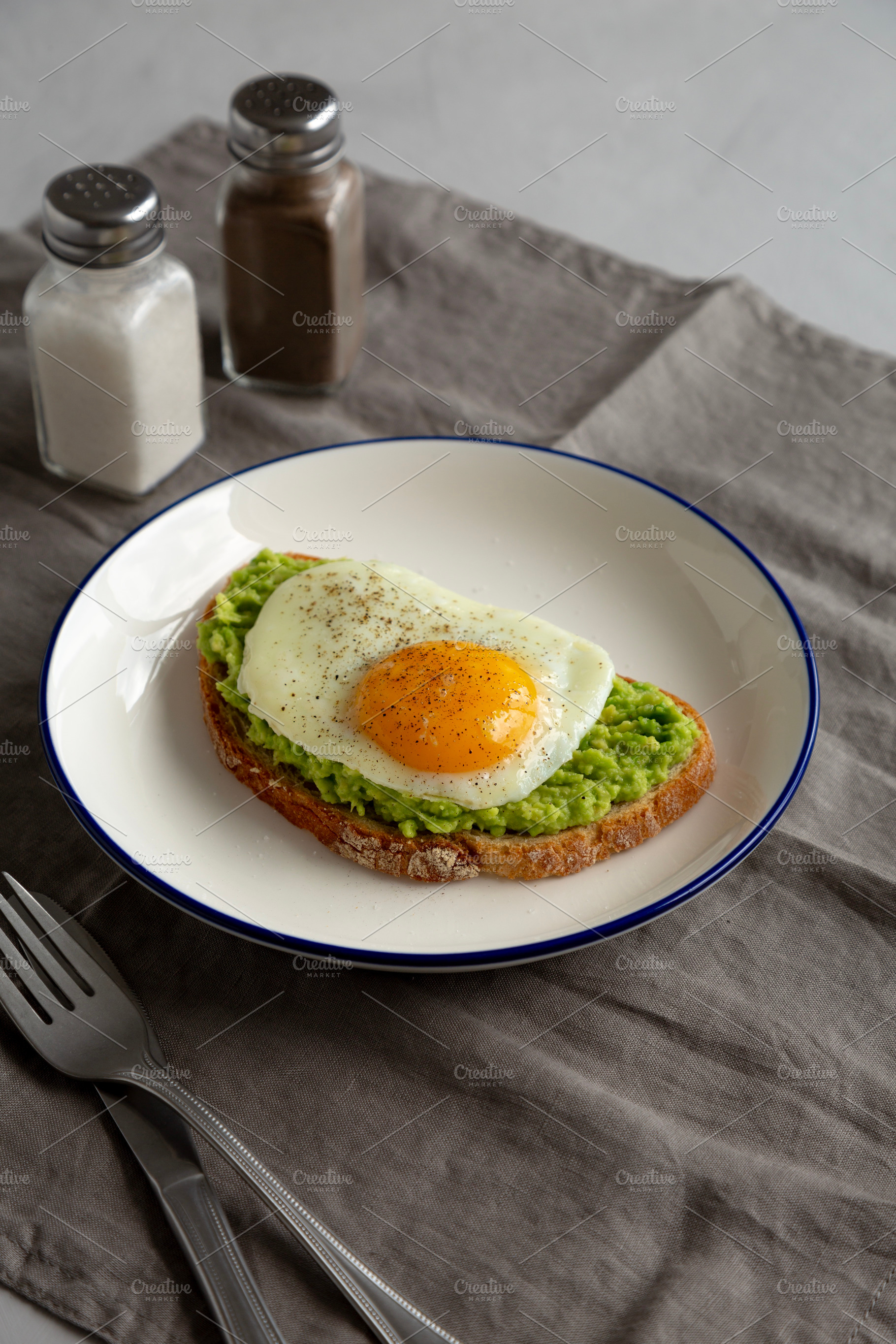 Homemade Avocado Toast with Egg on a Plate, side view., a Food & Drink Photo by LiudmylaChuhunova
