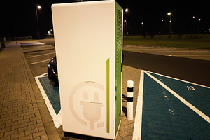 Nighttime electric car charging station in Poland parking lot with modern green, a Photo by AS photostudio