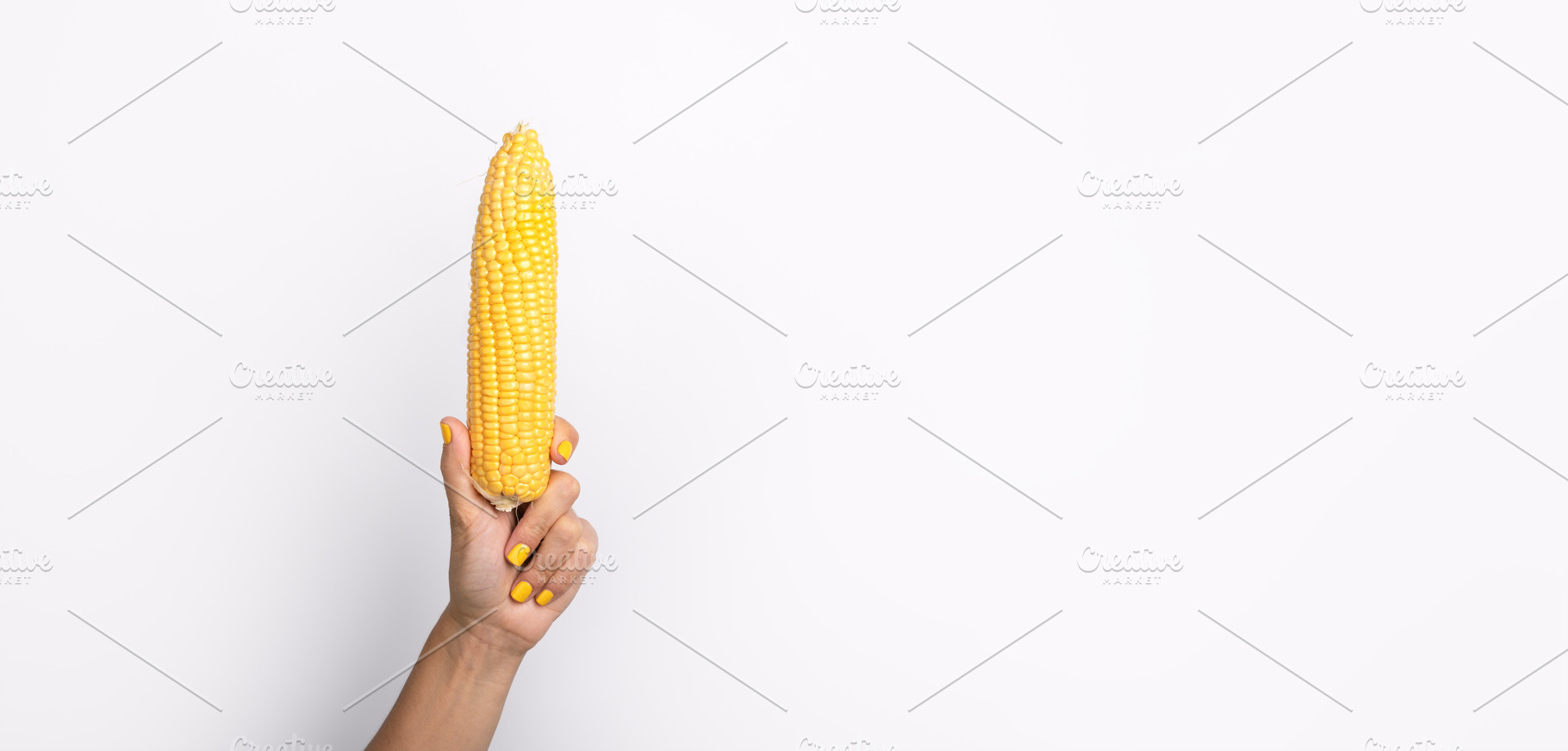 Female hand with yellow nail polish holding an ear of corn agai, a Food & Drink Photo by Ales Munt