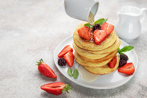 Pancakes with berries and syrup pouring for breakfast, a Food & Drink Photo by Olena Rudo