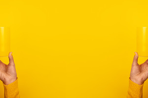 Symmetrical image of two hands in yellow sweaters holding yellow, a Food & Drink Photo by Ales Munt