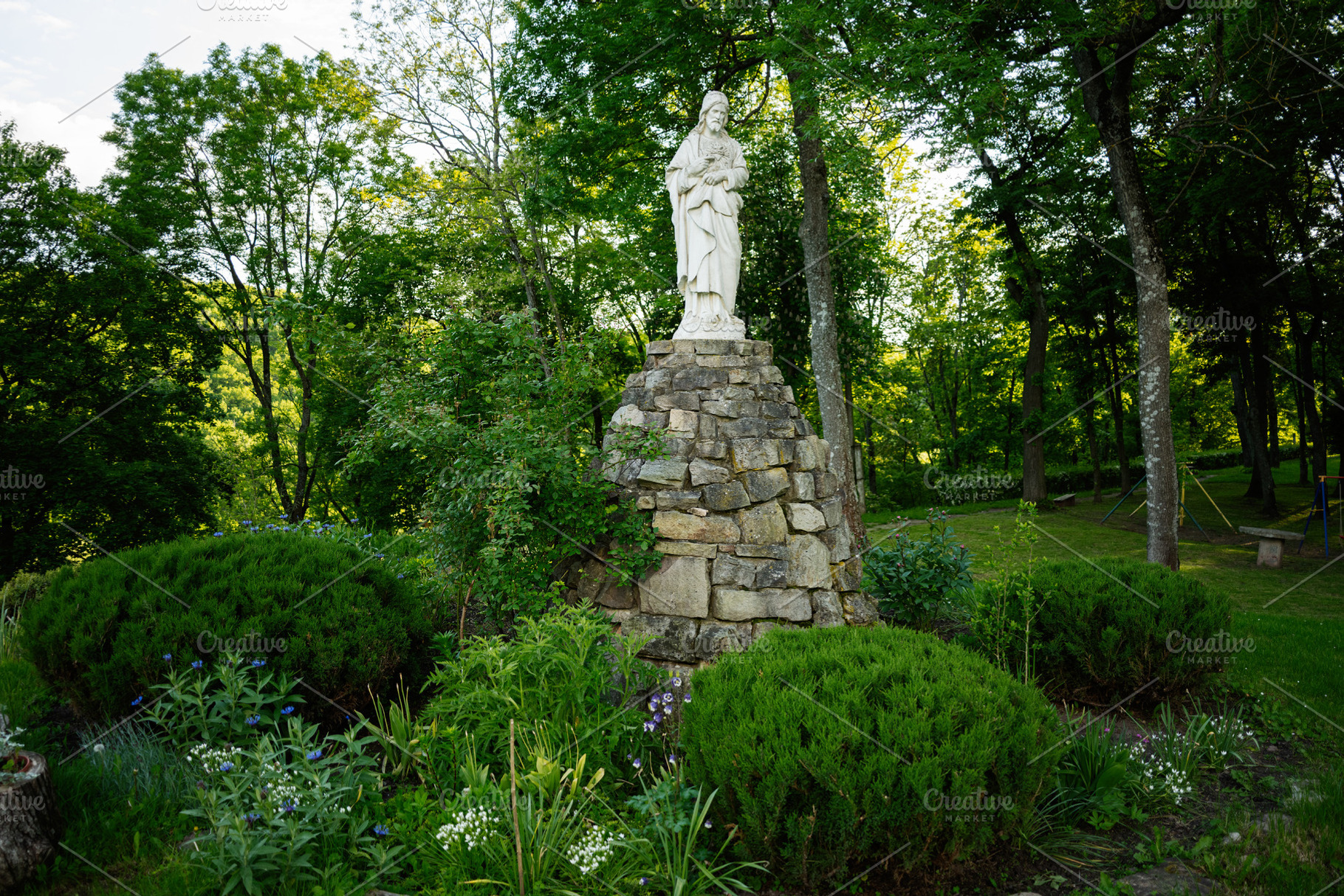 Marble statue of Jesus Christ in a peaceful garden surrounded by lush green tre, a Photo by AS photostudio