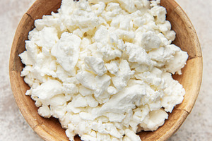 Cottage cheese in wooden bowl on rustic background, a Food & Drink Photo by Olena Rudo