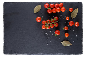 Cherry tomatoes and spices on a black slate board, top view, a Photo by ndanko