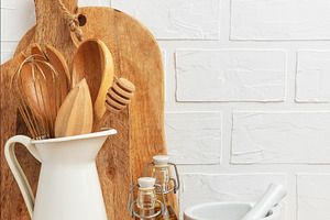 Kitchen utensils resting on wooden countertop with white brick w, a Food & Drink Photo by Olena Rudo