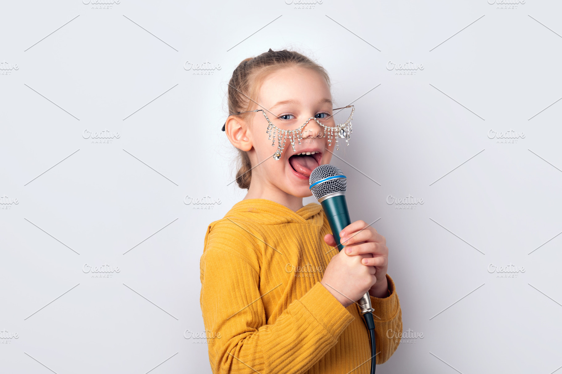 Cheerful young girl in yellow hoodie and playful glasses singing, a Person Photo by Ales Munt