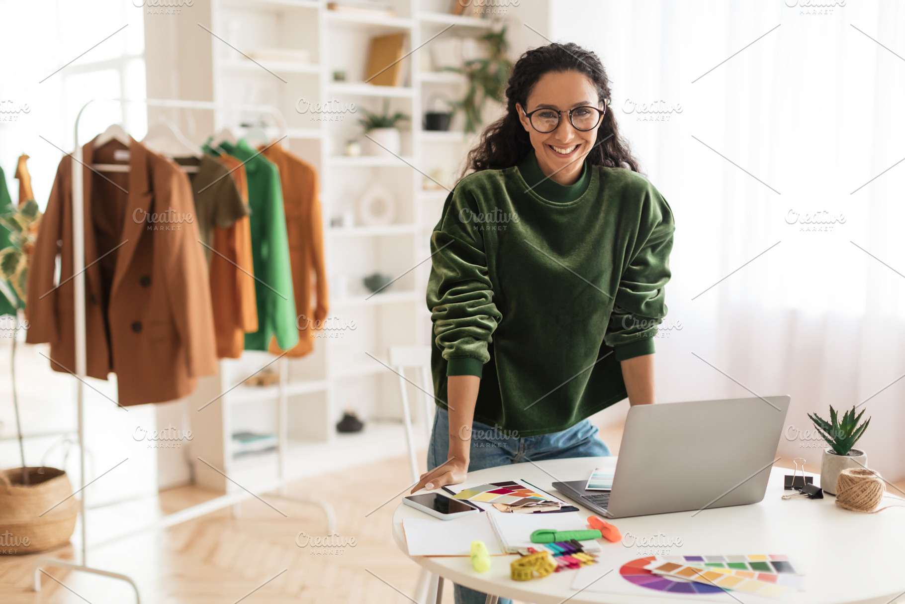 Happy Clothing Designer Lady Using Laptop Smiling Standing In Showroom, a Photo by Prostock-Studio