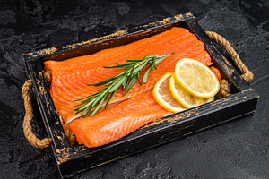 Uncooked salmon fillet with bright orange flesh rosemary and lem