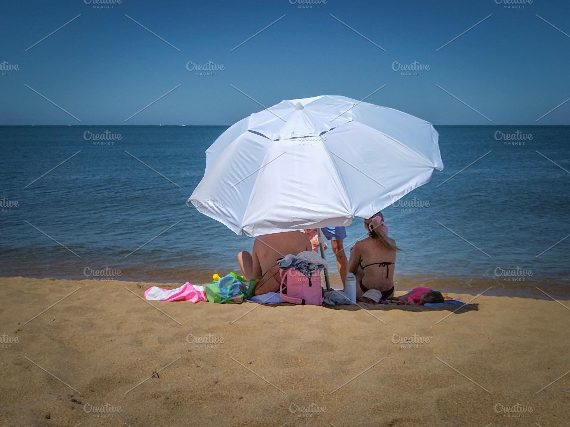 Couple relaxing under an umbrella on a sunny beach, a Person Photo by DanFLCreativo