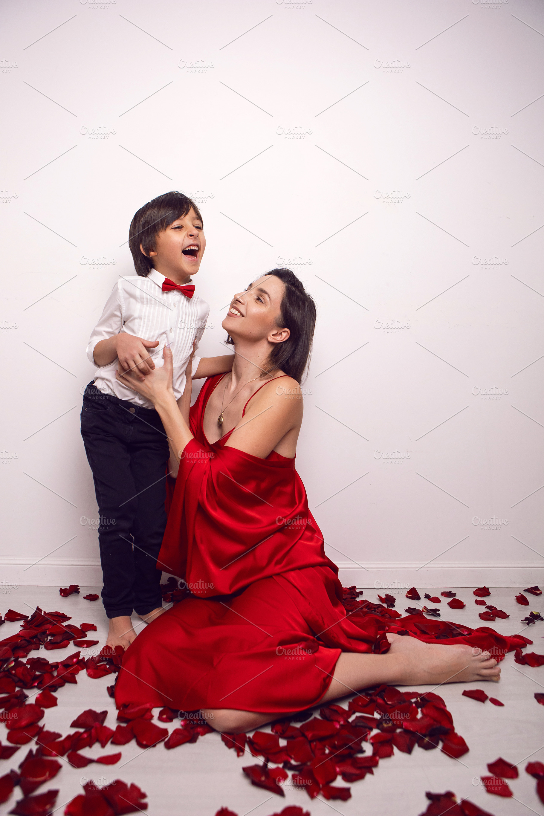mother in a red dress is sitting on the floor with a child, a six-year-old son, a Person Photo by SaulichPhoto