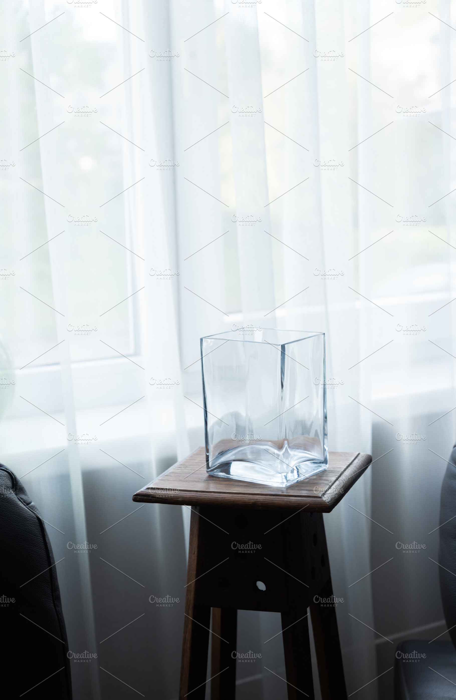 Empty glass vase on wooden stool near window in minimalist inter, an Industrial Photo by MDBildes