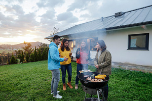 Group of friends grilling outdoors in stormy day, a Person Photo by DanFLCreativo