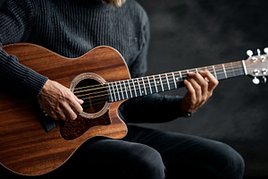 Expert musician plays acoustic guitar in dim studio setting, a Photo by OSORIOartist