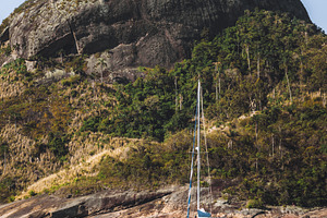 Rocky island behind blurred sailboat, a Sports & Recreation Photo by SkyNext