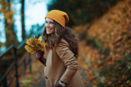 happy stylish woman in brown coat and hat enjoying promenade, a Person Photo by Alliance Images