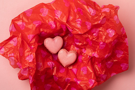 Two heart shaped macarons on red tissue paper