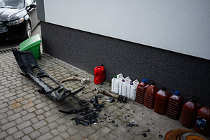 Discarded car parts and plastic containers by a building wall, a Transportation Photo by AS photostudio