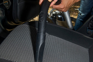 a man vacuuming the seat of a car, a Photo by Nito