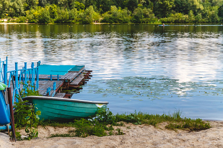 Green old boat is tied to the old wooden pier on the river bank., a Nature Photo by TanaCh