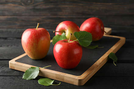 Apples and cutting board on wooden background, space for text, a Food & Drink Photo by AtlasStudio