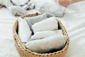 Woman folding clothes in jute basket in the konmari system. Conc