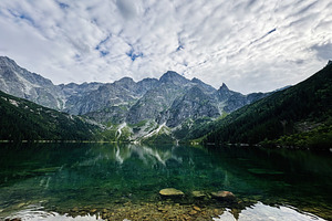 Tranquil alpine lake surrounded by jagged mountains in Zakopane Poland with cle, a Nature Photo by AS photostudio