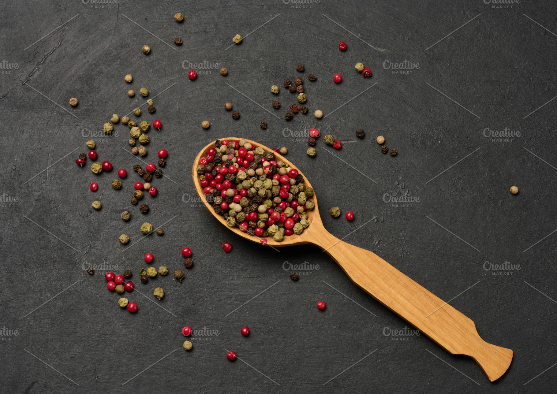 Mixed dry peppercorns in a wooden spoon on a black table, top vi, a Food & Drink Photo by ndanko
