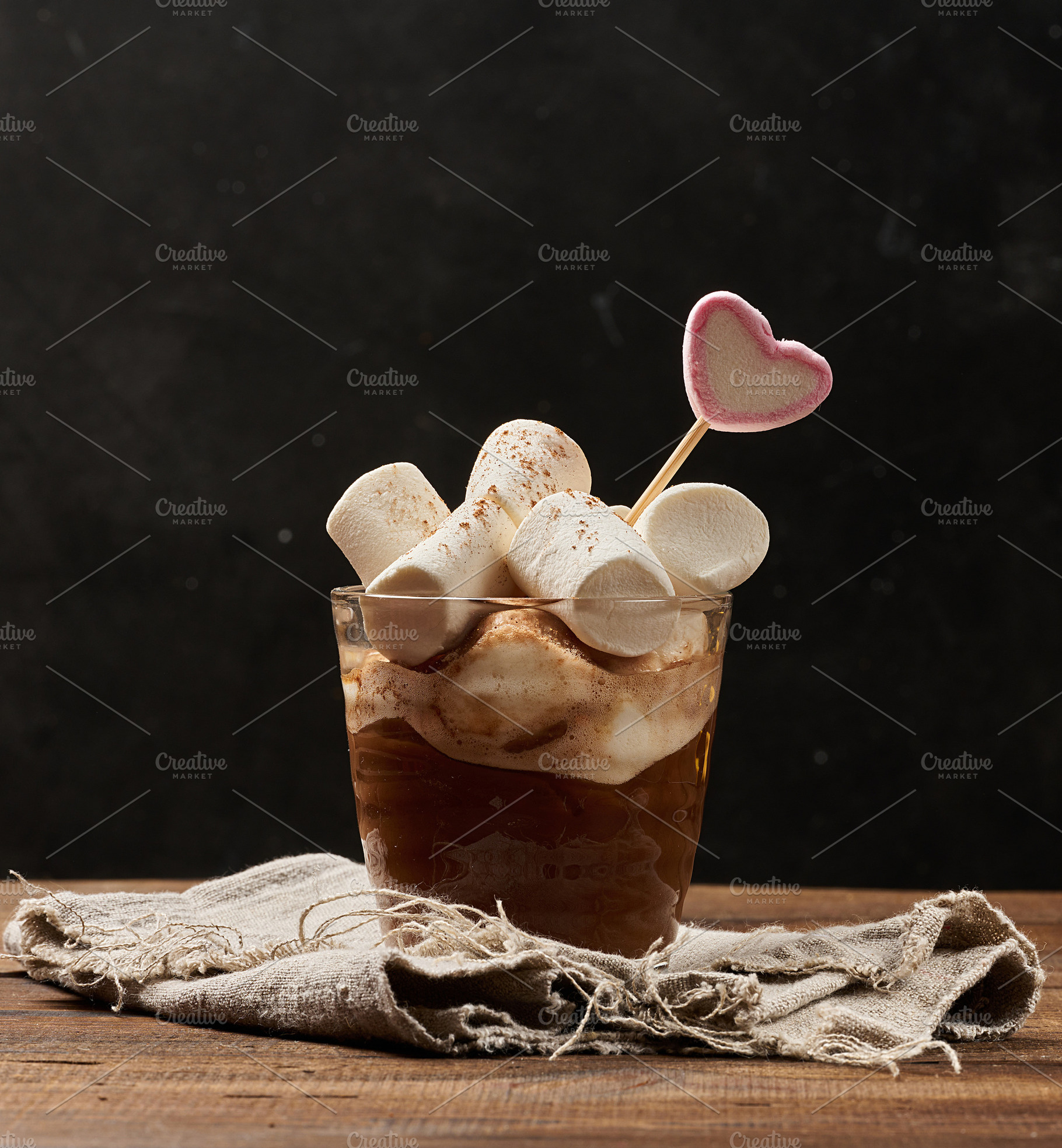 A glass of hot chocolate with fluffy marshmallows on a wooden ta, a Food & Drink Photo by ndanko