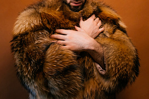 Stylish man wearing a yellow beanie, sunglasses, and fur coat, a Photo by karrastock