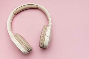 Modern wireless headphones lying on pink background, a Technology Photo by Olena Rudo