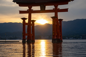Famous red torii gate of Itsukushima shrine at sunset in Miyajim