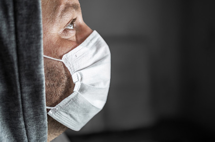 Young tired man in a hood and a medical mask look up with hope,, a Person Photo by TanaCh