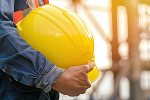 Yellow safety helmet in worker hands on blurred background, a Photo by AlyaAnd