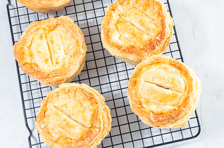 Small beef pot pies on cooling rack, top view, square, a Food & Drink Photo by iuliia_n