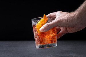 Hand Holding Old Fashioned Cocktail with Orange Peel in Crystal Glass, a Food & Drink Photo by etorres69