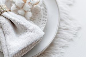 Elegant table setting with a gold napkin ring and cotton branch, a Photo by Studio ANNA