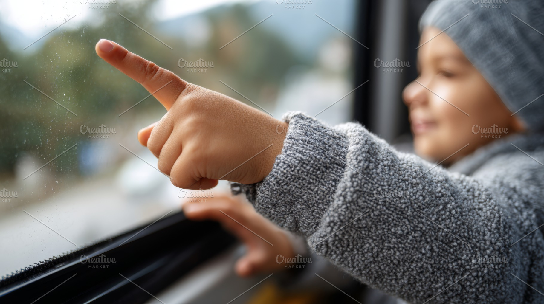 A joyful child points at raindrops on the bus window, wearing a cozy gray sweat, a Business Photo by ImageMir