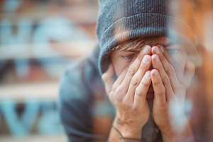 Young man in a hoodie sits with face, a Person Photo by MistyDay