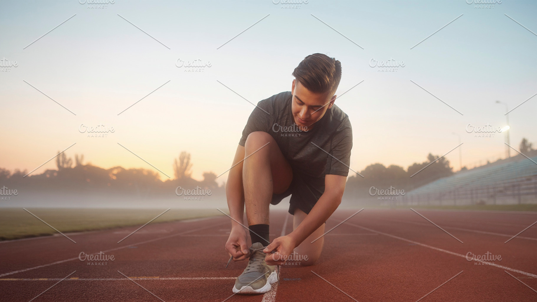 Runner tying shoe on track at foggy morning, a Photo by DanFLCreativo