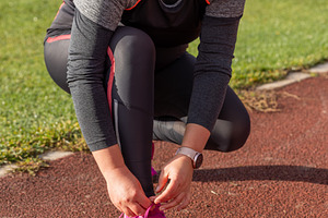 Woman tying shoelaces, a Photo by Grafvision photography