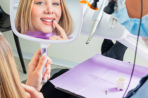 Young woman admiring her smile after dental procedure, a Health & Medical Photo by Antonio Gravante Market