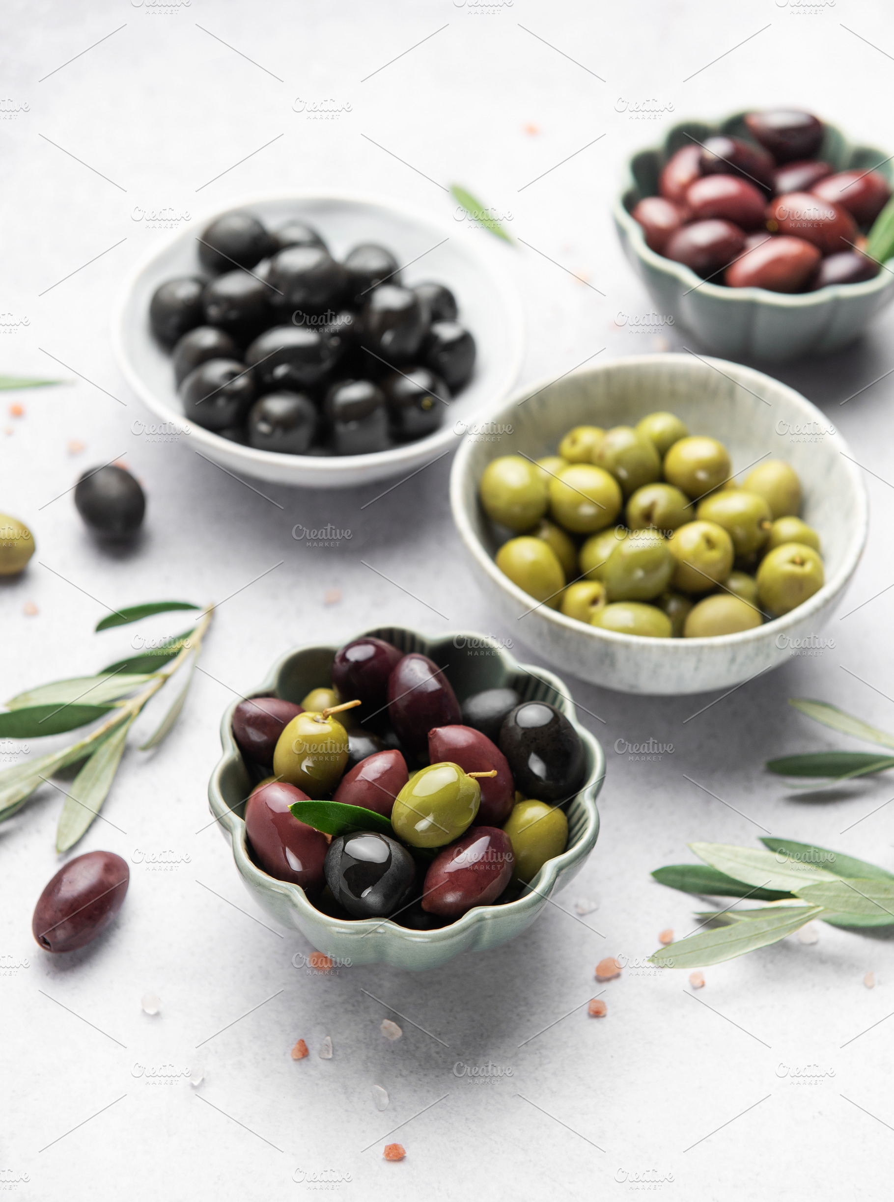 Assorted olives in decorative bowls on white surface, a Food & Drink Photo by Olena Rudo