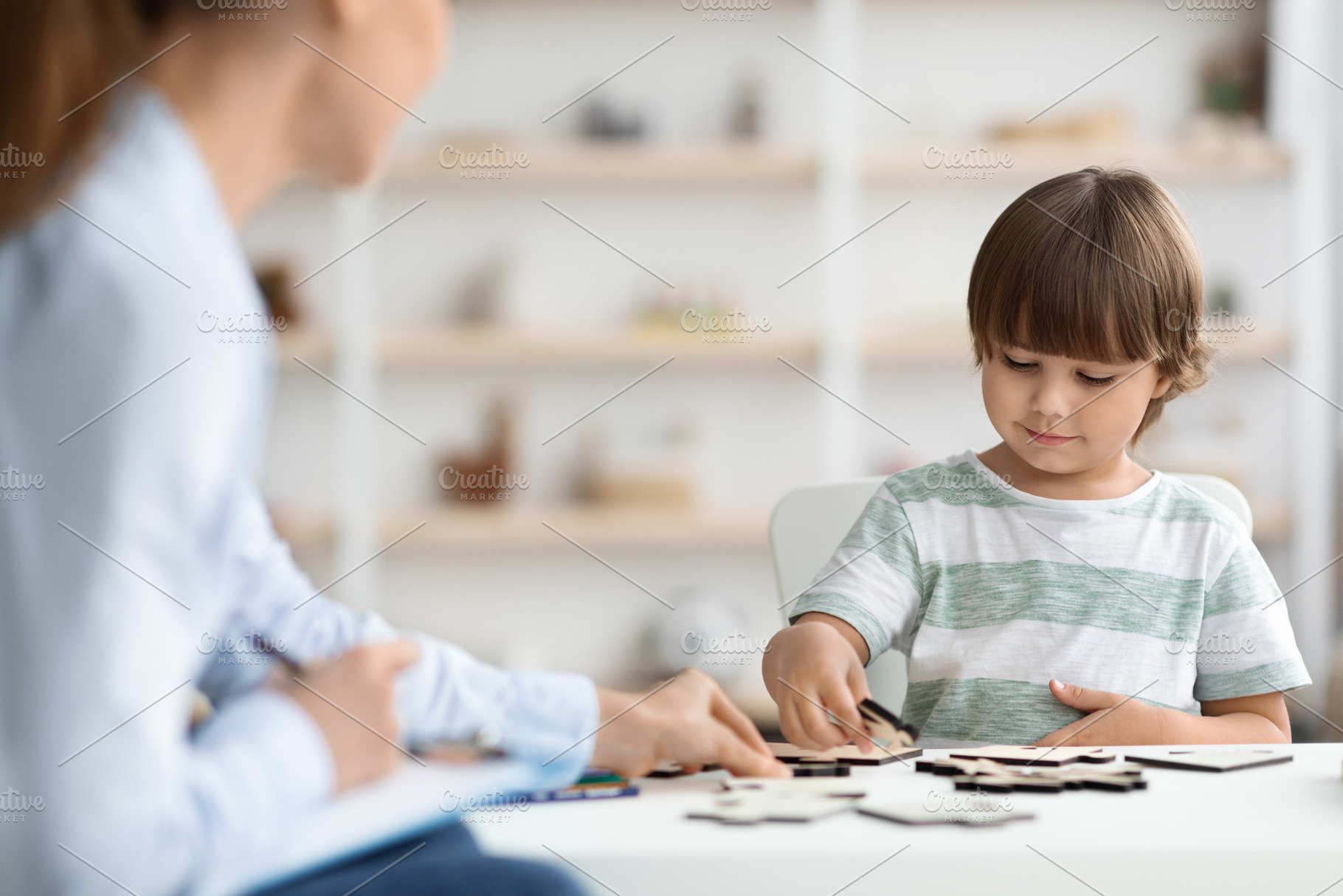 Cute clever little boy playing with eco-friendly wooden figures at office, woma, a Photo by Prostock-Studio