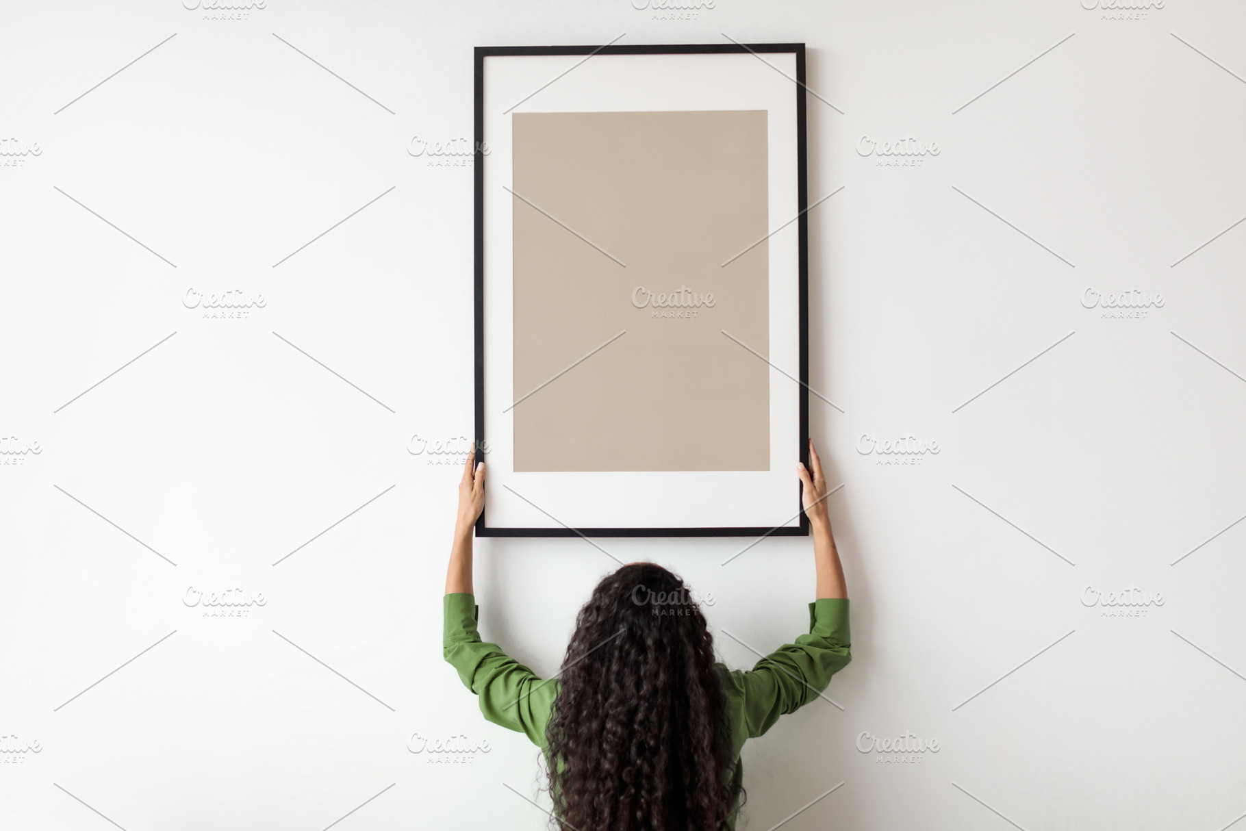 Unrecognizable Female Hanging Blank Poster In Frame On Wall Indoor, a Photo by Prostock-Studio