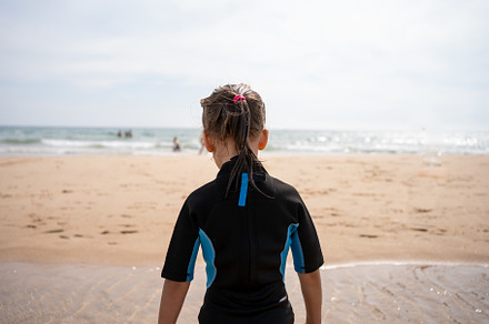 Little girl surfer in wetsuit standing ocean beach, a Person Photo by andreonegin market